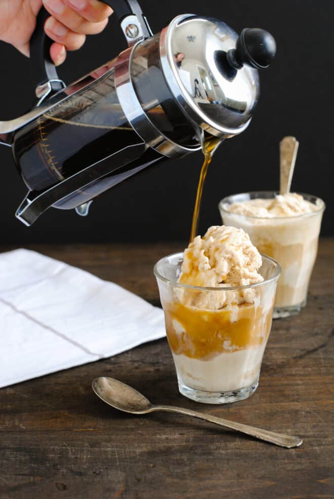 Two small glasses of ice cream, with a person pouring coffee from a French press over the ice cream.