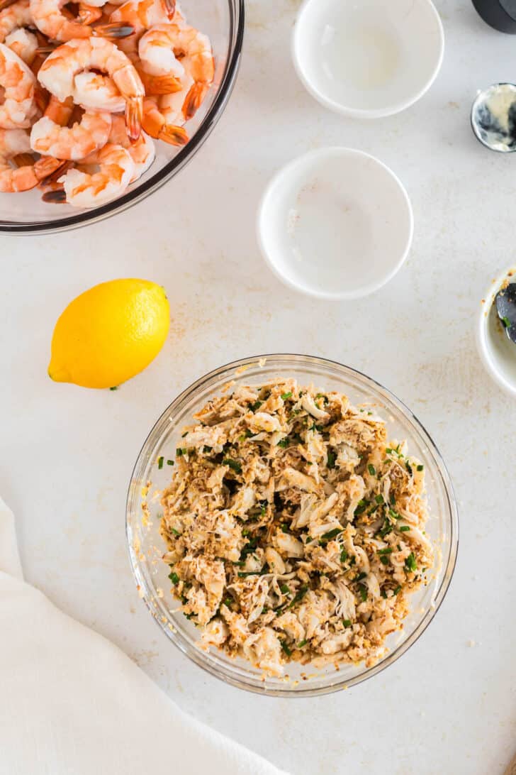A mixture of crab meat, herbs and breadcrumbs in a glass bowl.