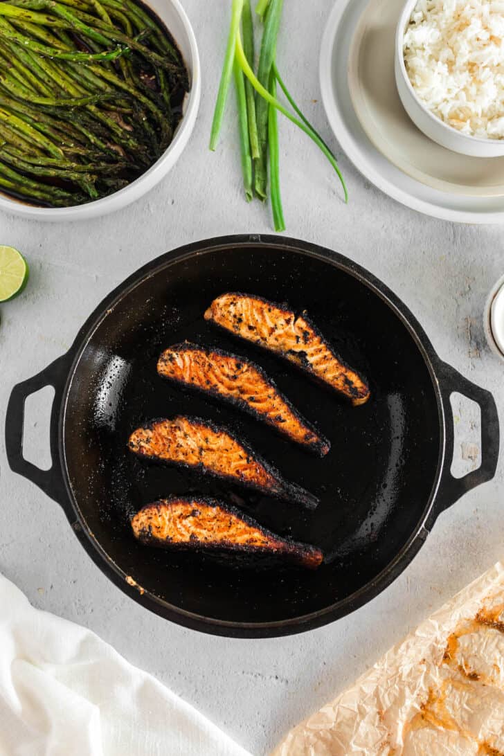 Four pieces of blackened salmon in cast iron skillet.