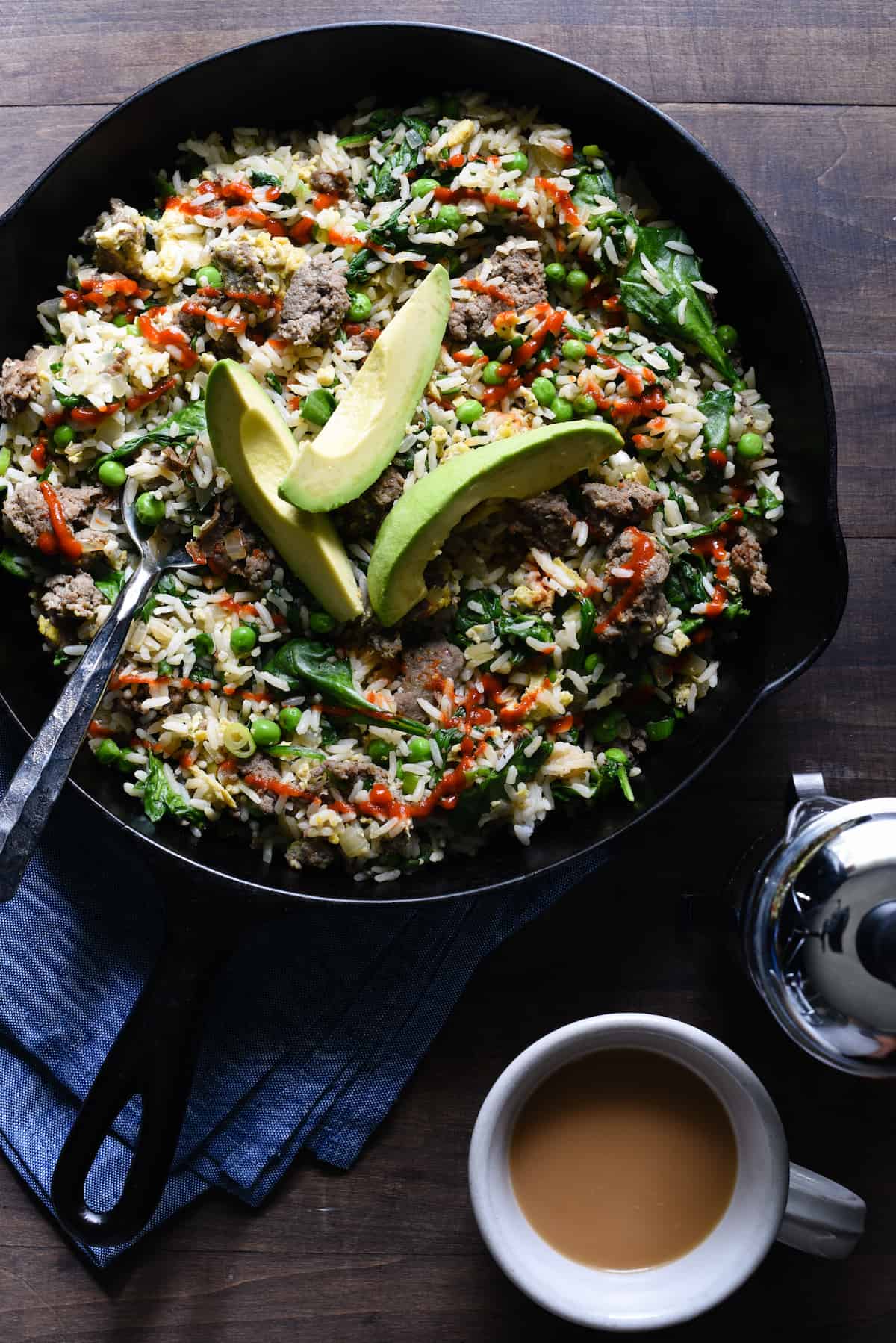 Cast iron skilled filled with breakfast fried rice, topped with avocado slices.