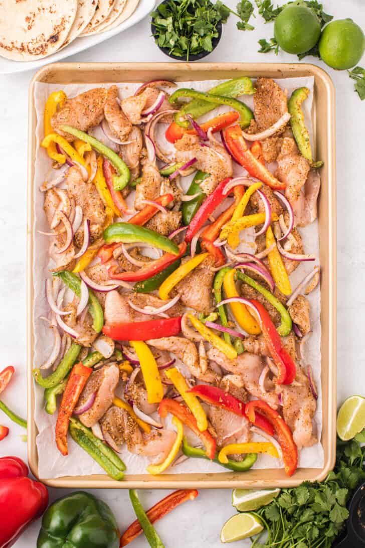 Sheet pan fajitas chicken made with tri-color bell peppers and red onion, ready for the oven.