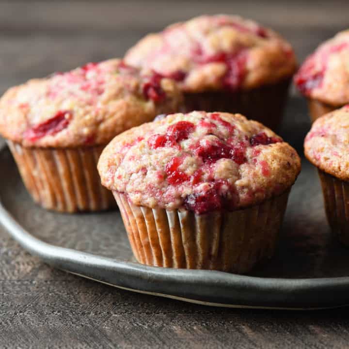 Five cranberry muffins on a gray plate.