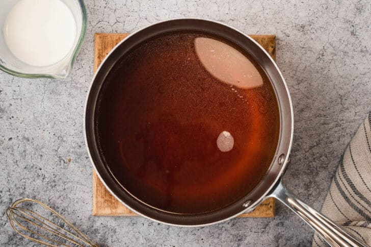 A stainless steel saucepot filled with brown broth.