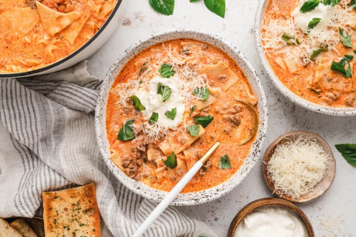 Easy Lasagna Soup in rustic bowls, topped with ricotta, Parmesan cheese and fresh basil.
