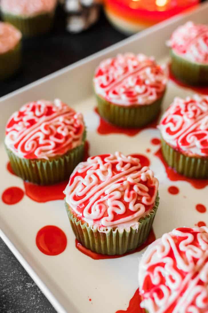 Halloween cupcakes piped with frosting to look like bloody zombie brains, on a white platter.