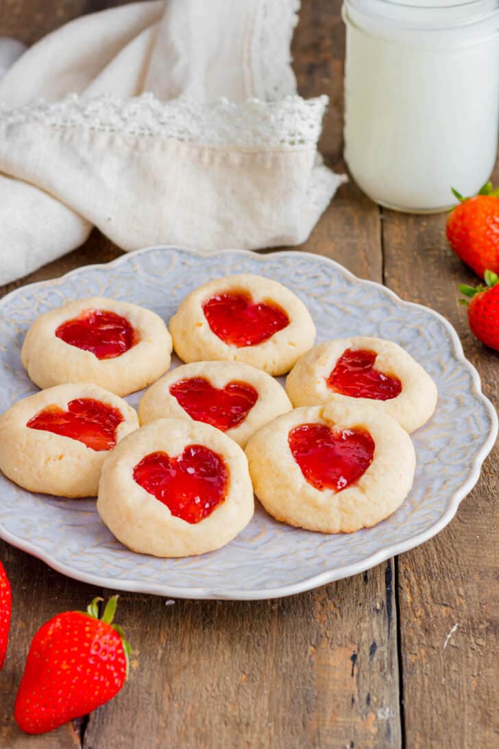 Jam heart cookies on a decorative plate on a wooden surface.