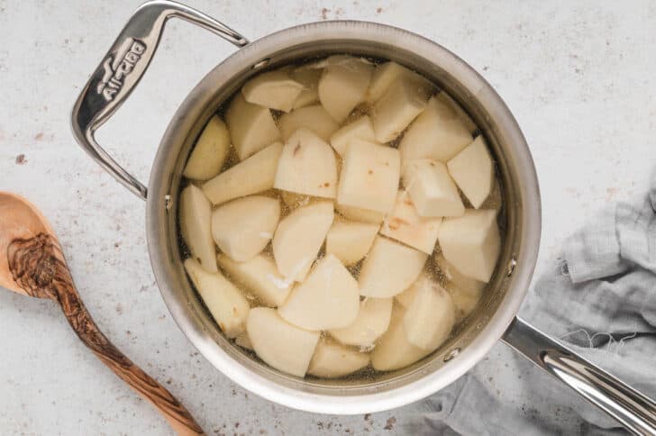 A stainless steel pot filled with cubed potatoes and water.