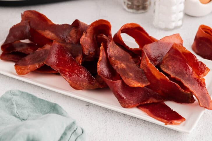 Cooked rashers arranged on a white rectangle platter.