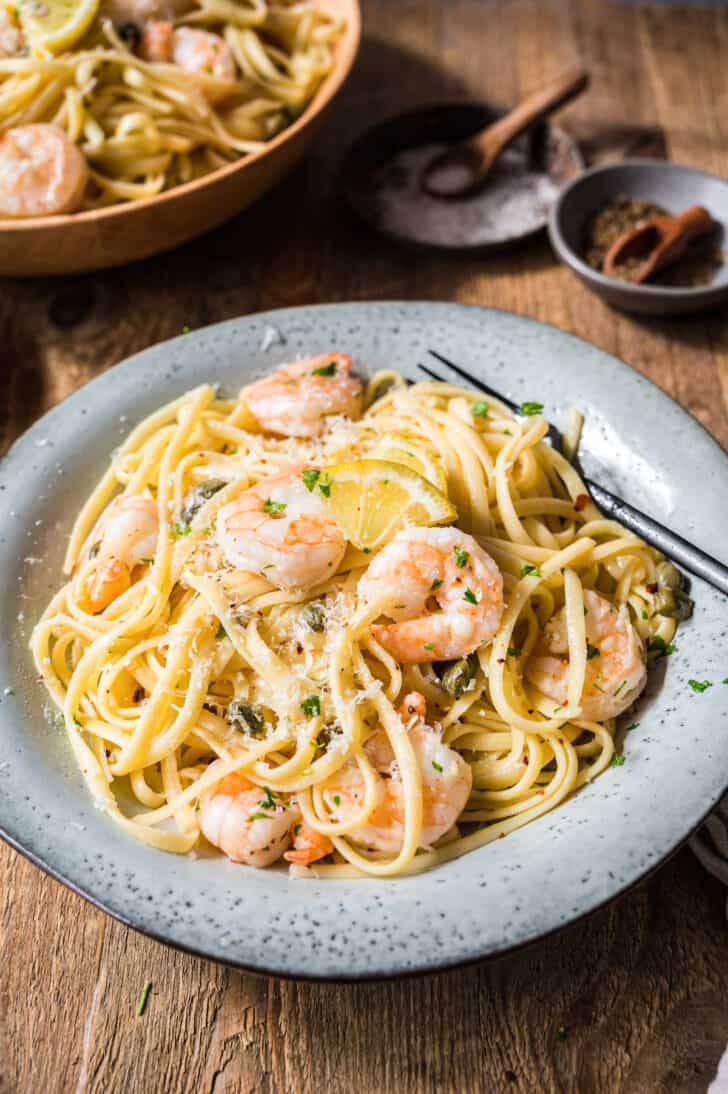 A rustic gray bowl filled with linguine, shrimp, lemon sauce and Parmesan cheese.