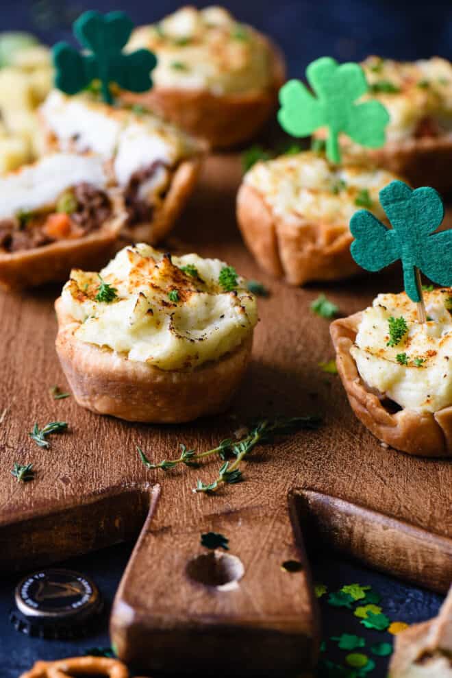 Mini shepherd's pie made with pie crust in muffin cups, decorated with St. Patrick's Day shamrock decorations.