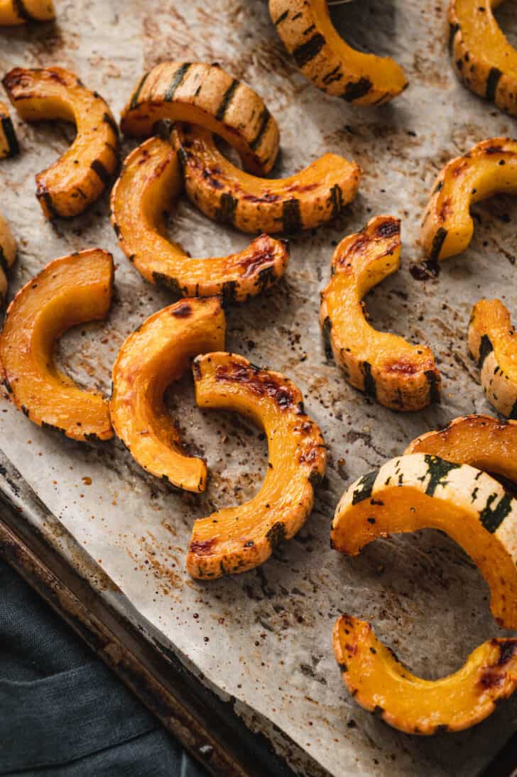 Delicata squash half moons that have been roasted on a sheet pan.