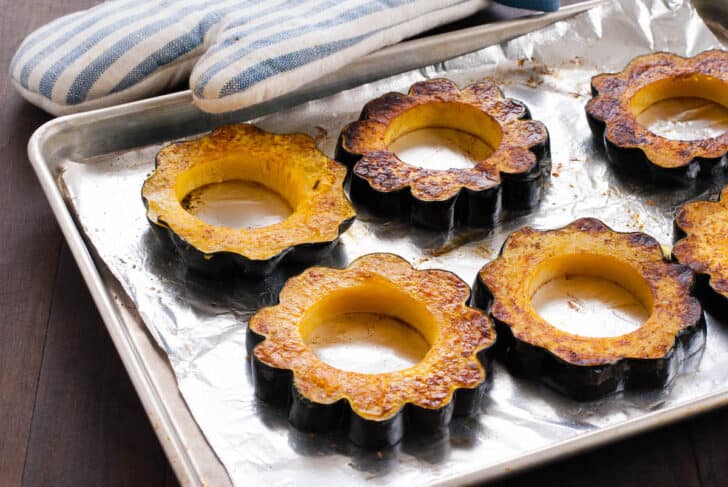 Oven roasted acorn squash rings on a rimmed baking pan covered in foil.