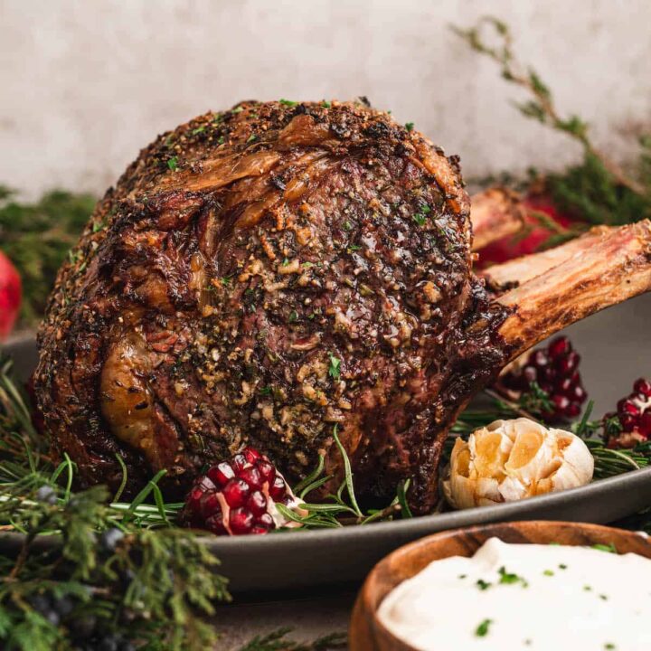 A standing rib roast covered in prime rib rub in a festive holiday dinner table scene.