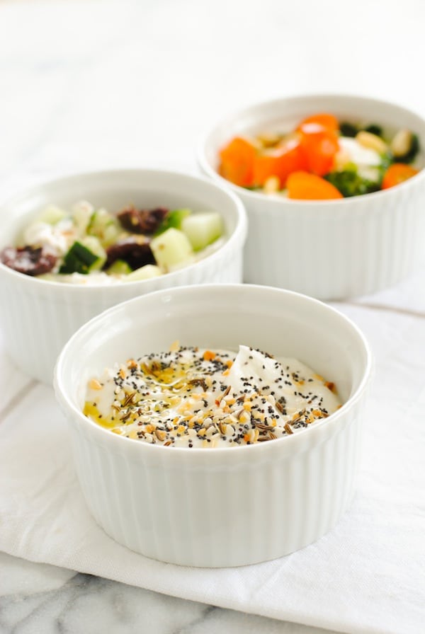 Closeup of ramekin of everything bagel yoghurt. Greek and Caprese topped yogurts in background.