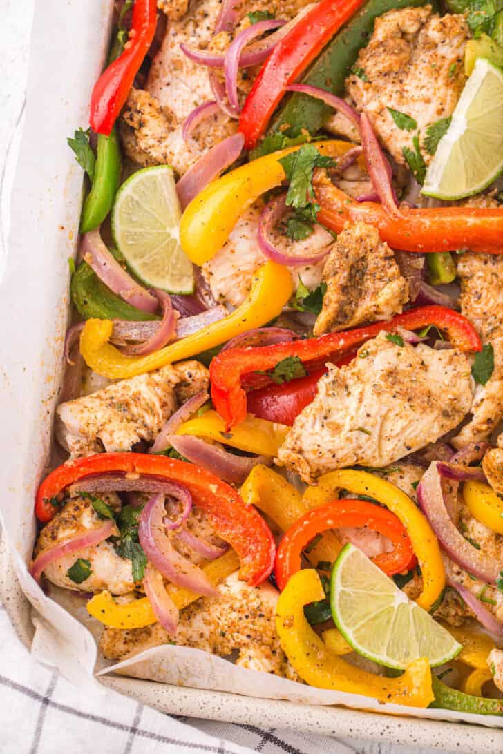 A chicken fajitas sheet pan dinner garnished with a lime wedge.