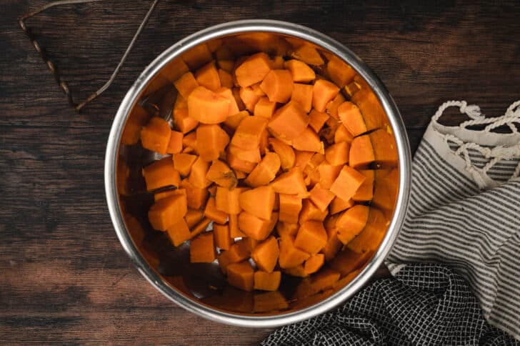 Cubed orange vegetables in a metal bowl.