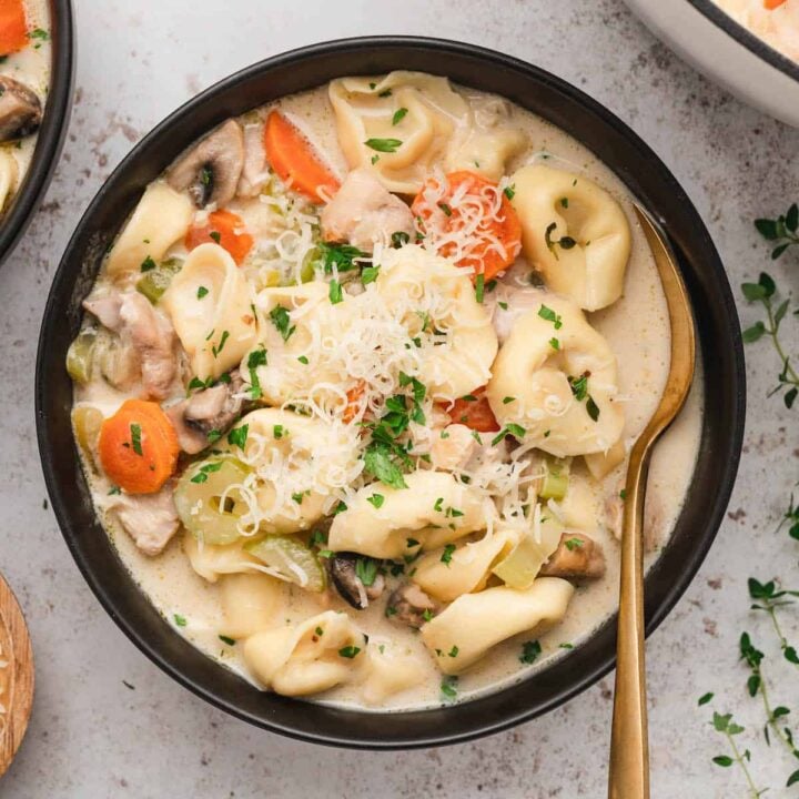 Black bowl filled with creamy chicken tortellini soup.