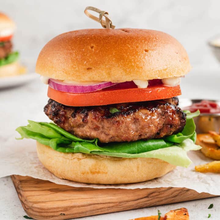 A turkey burger on a brioche bun with lettuce, tomato, onion and mayonnaise.