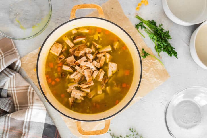 A white Dutch oven with the best turkey soup recipe in it.