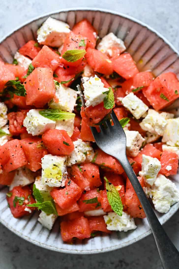 A textured gray filled with watermelon feta mint salad
